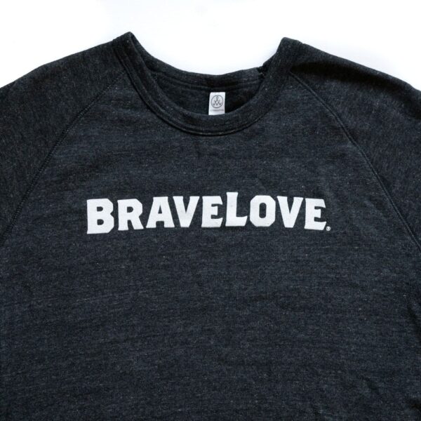 A charcoal grey sweatshirt with the word "BRAVELOVE" printed in bold, white, uppercase letters on the front.