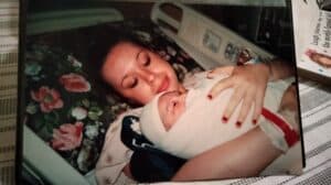 A woman lying in a hospital bed holding her newborn baby wrapped in a blanket.